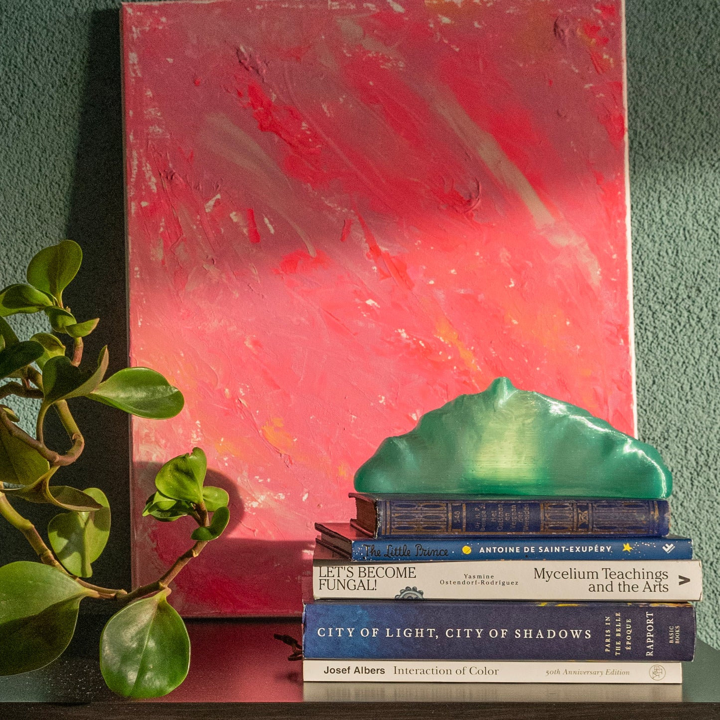 Croissant lamp on a stack of books with against a pink abstract painting