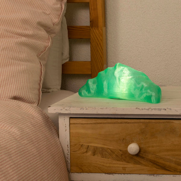 Green croissant lamp on a wooden nightstand