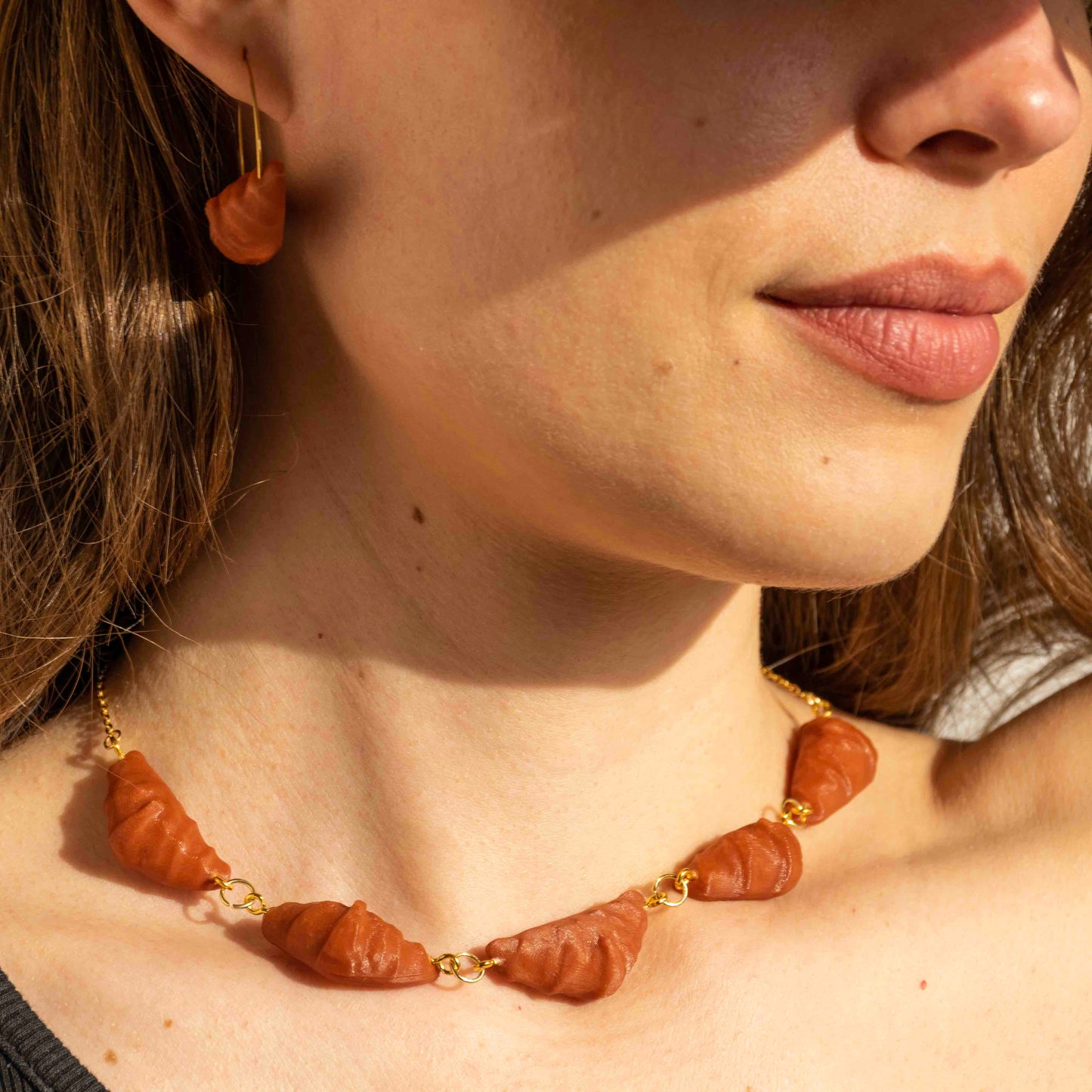 cute, statement collar necklace. gold stainless steal. clay red color. croissant shaped