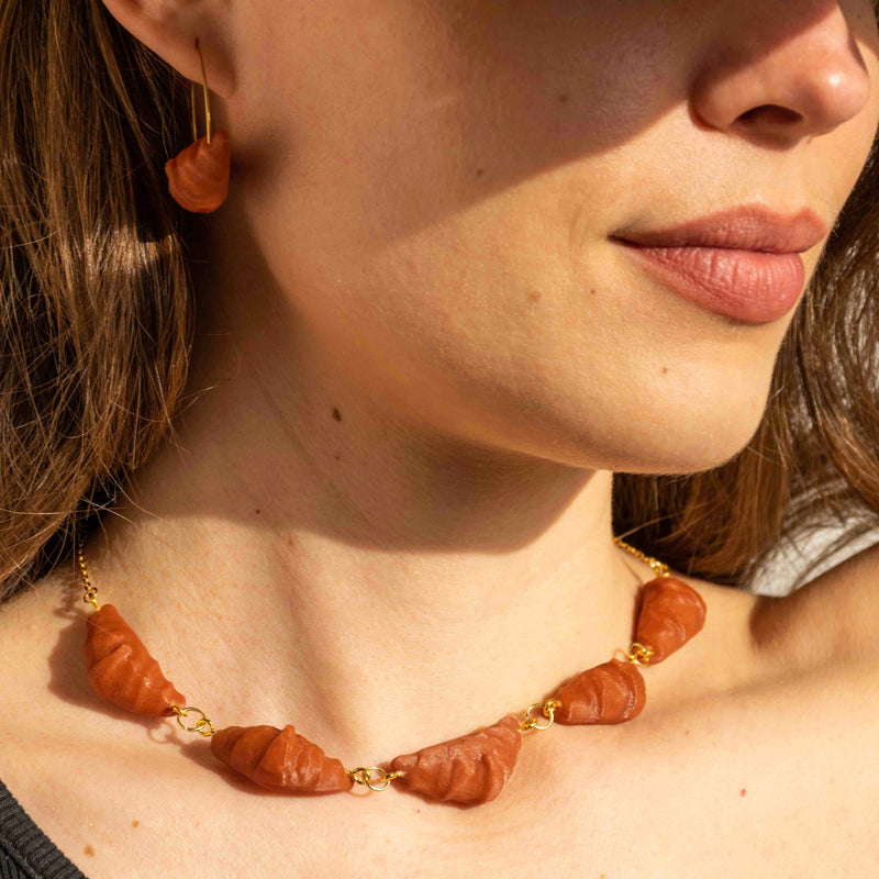 cute, statement collar necklace. gold stainless steal. clay red color. croissant shaped