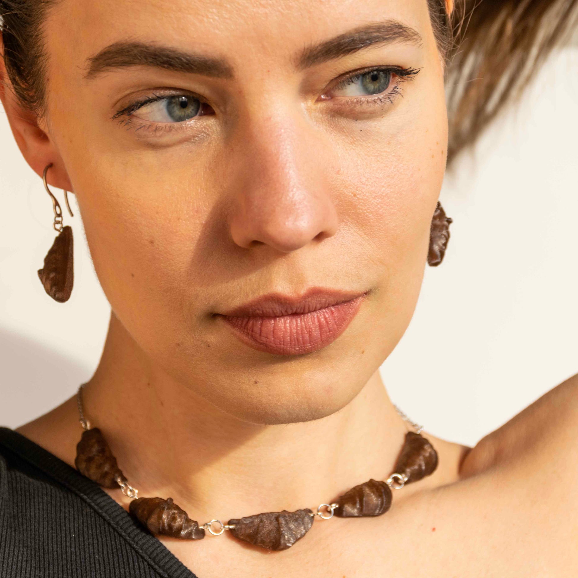 cute, statement collar necklace. silver stainless steal. coffee brown color. croissant shaped. sustainable locally made nacklace