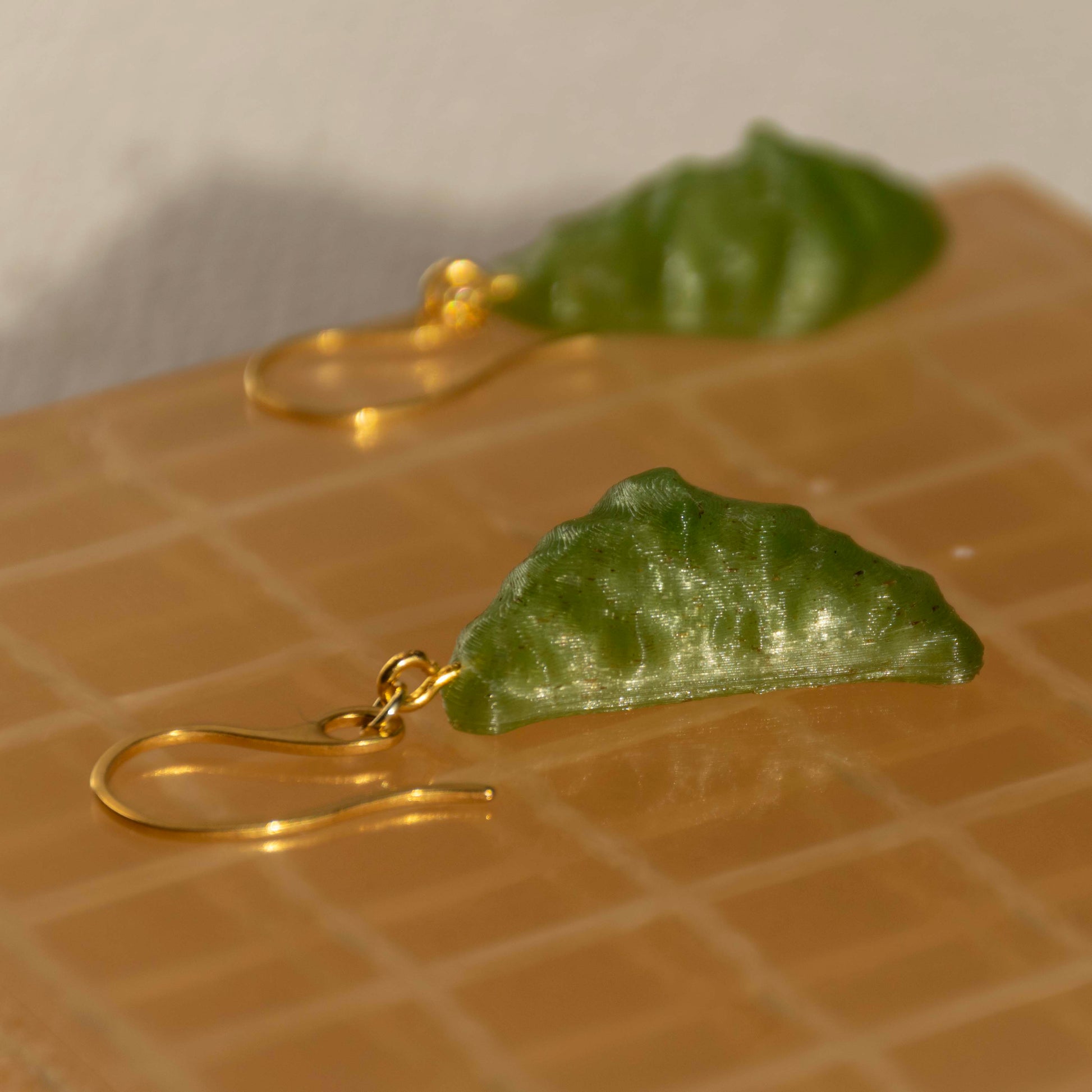 Hemp croissant earrings with gold hooks on a textured surface
