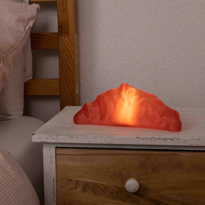 Pink croissant lamp on a wooden nightstand.